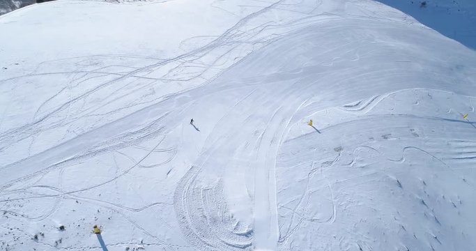 aerial follow over skier alpine skiing in winter snowy mountain ski track field in sunny day.Above Alps mountains snow season active ski sport people.4k drone flight