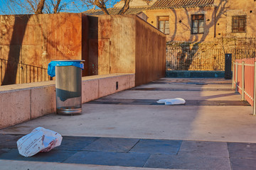 Remains of garbage and trash of plastic bags and trash can at sunrise in a park in Toledo, Spain