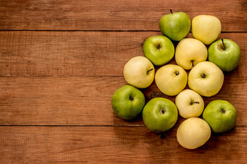green and yellow apples on a brown wooden background
