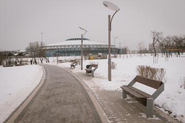 Snow-covered trees and benches in the city park.