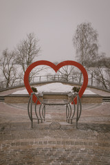 Snow-covered trees and benches in the city park. An elderly man in a recreation park