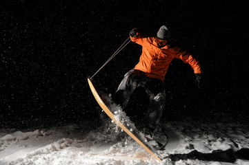 Professional male snowboarder jumping on snow at night