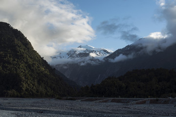 Paisaje de picos de montañas nevados y verdes con cielo nublado en Nueva Zelanda