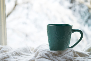 Obraz na płótnie Canvas Cup Of Hot Coffee With White Warm Plaid On Windowsill Window Of House Winter.