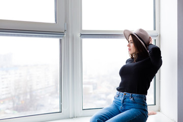 Beautiful boho woman in wool hat sitting by the window