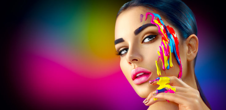 Beauty model girl with colorful paint on her face. Portrait of beautiful woman with flowing liquid paint