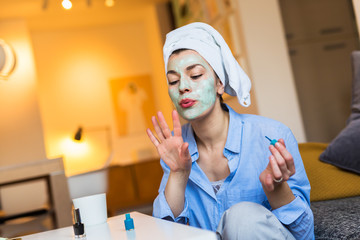 Preparing for party tonight. Woman with face mask polishing nails.