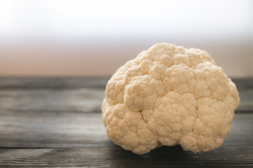 a piece of fresh cauliflower on a wooden table surface in backlight with a copy space 