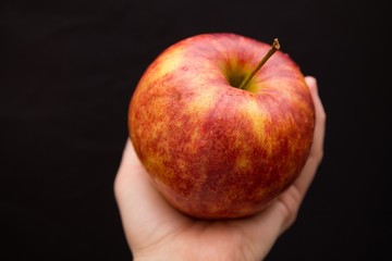 a ripe red and yellow apple in woman's hand