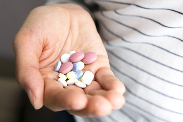 Closeup on pills pack in hand of ill young woman laying on sofa