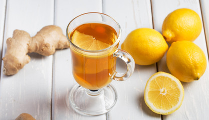 A cup of ginger tea with lemon on a wooden background.