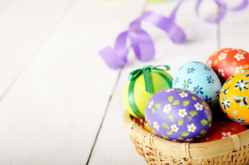 Rustic style painted easter eggs in basket on white table