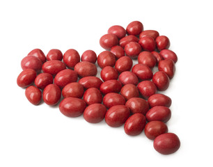 Candy covered with red icing and lined in a heart shape on a white background. Valentine's Day