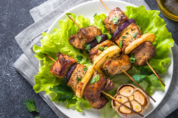 Grilled shish kebab or shashlik on black stone table.