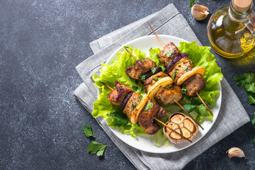 Grilled shish kebab or shashlik on black stone table.