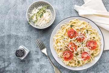 cooked noodles on a table in a plate with tomatoes, parmesan cheese and spices