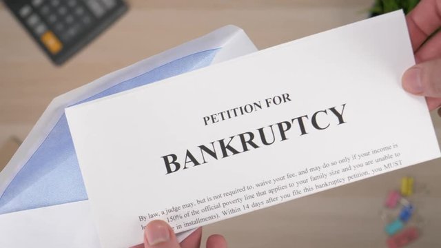 Opening a letter with a Bankruptcy document inside.