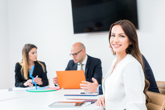 Beautiful business woman is looking at camera and smiling while working in office