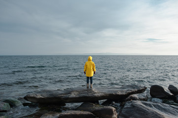 Human in yellow raincoat stand in front of sea - 192728794