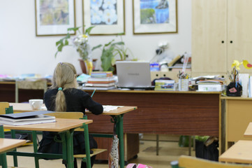 Little girl sits at a desk in a classroom for painting
