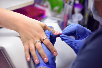 Obraz na płótnie Canvas Manicurist prepares a form for creating a nail from the gel