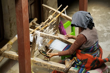  Nepalese woman manually braids the mat on an old homemade loom, in the city of Lo Mantang, the...