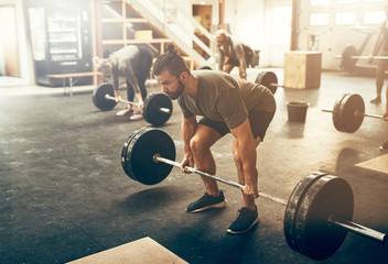 Fit young man lifting heavy weights during a workout session