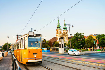 Fototapeta premium Yellow Tram moving by the embankment with St Anne Church