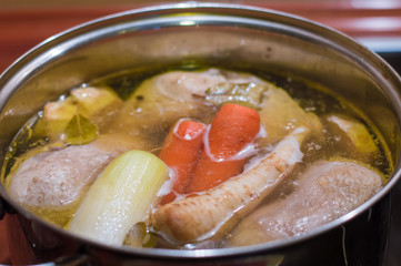 Chicken broth with vegetables being cooked in the pot.