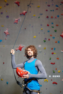 Young active man with climbing gear on background of climb wall