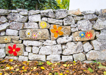 Muretto a secco. Old traditional stone wall with painted flowers in Puglia, Italy