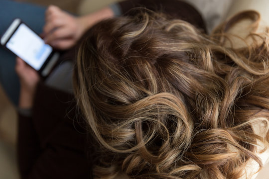 Donna mentre usa lo smartphone seduta sul divano