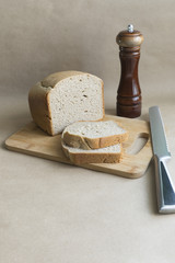 homemade bread on the board a knife and a pepper mill
