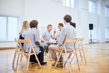 Irritated young man trying to explain his problems to psychologist among groupmates during session