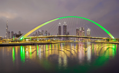 Fototapeta na wymiar Bridge over water canal with reflection and Dubai skyline, United Arab Emirates