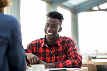 Smiling African-american businessman having working discussion with colleague in cafe
