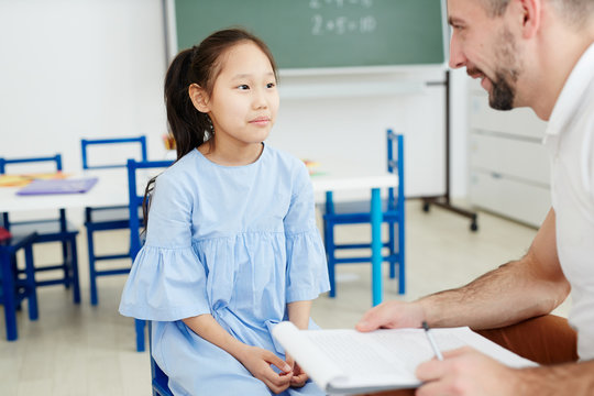 Serious schoolgirl listening to her teacher or school psychologist advice