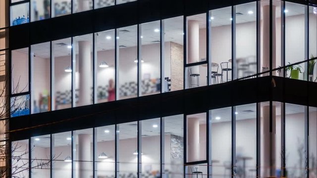 Office windows at night with white collars inside. Office work overtime. Time lapse