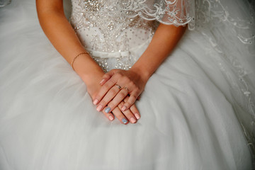 Hands of the bride against a white dress. Wedding manicure