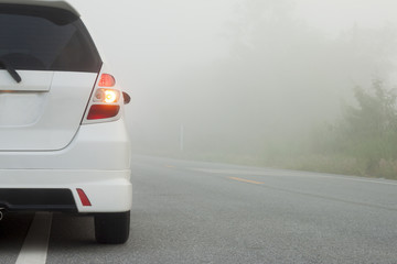 The back of the car break on the road with foggy on morning.