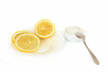Lemon on a plate and sugar on a white background. Slices of lemon. 