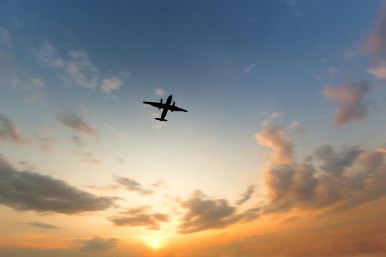 Silhouette Of Turboprop Airplane Flying In Orange Sky At Sunset, Wide Angle, Focus On Plane, Blurred Clouds, Copy Space/ View Of A Flying Airplane From Below/ Vacation, Aviation, Trip Concept