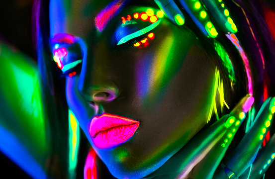Fototapeta Fashion model woman in neon light. Portrait of beautiful model girl with colorful fluorescent makeup
