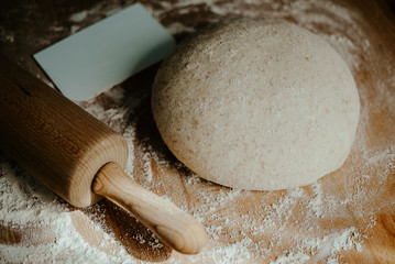 Whole wheat pizza dough shaped into ball on floured wooden background