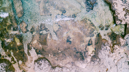 Aerial view of waves break on rocky beach. Sea waves on the beautiful colorful rocky beach. Aerial view drone 4k shot. Zoom in