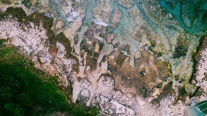 Aerial view of waves break on rocky beach. Sea waves on the beautiful colorful rocky beach. Aerial view drone 4k shot. Zoom in