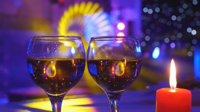 Valentine's Day Romantic Dinner. Date. two glasses over holiday blinking red background with hearts. Wedding celebrating, Table setting with candles and gift. Slow motion 4K UHD video