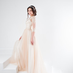 Portrait of a beautiful girl in a wedding dress. Bride in a luxurious dress standing on the stairs, climb up