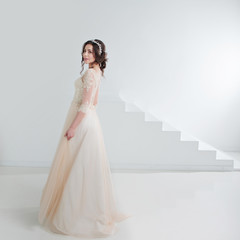 Fototapeta premium Portrait of a beautiful girl in a wedding dress. Bride in a luxurious dress, in a beautiful white interior