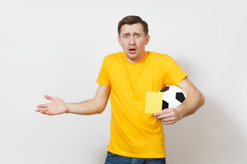 European sad upset crying shocked young man, football fan or player in yellow uniform hold in hand yellow soccer card for retire from field isolated on white background. Sport play, lifestyle concept.